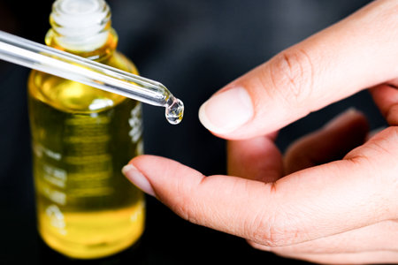 hands of a beautiful woman Dropping serum collagen moisturizer of face into clear gold bottle soft light background. Protector skin Treatment facial essence oil, Vitamin C. Beauty and spa Conceptの写真素材