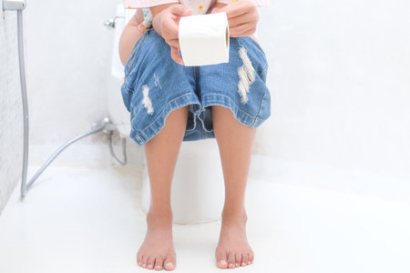 Woman sitting in the toilet bowl. In the bathroom, his home is unhappy with constipation, diarrhea, food poisoning, health and medical concepts.の写真素材
