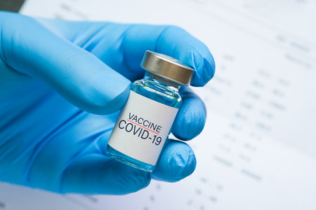 doctor's hand holds a syringe and a blue vaccine bottle at the hospital. Health and medical concepts.の写真素材