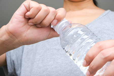 A woman opens a water bottle. She was about to drink water because it was hot.