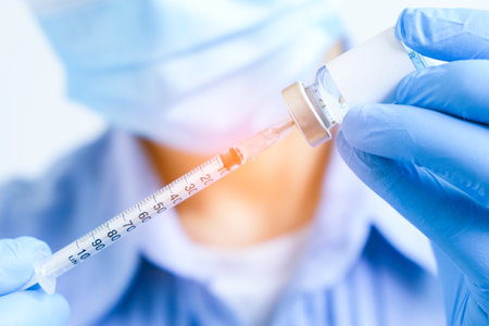 doctor's hand holds a syringe and a blue vaccine bottle at the hospital. Health and medical concepts.の写真素材