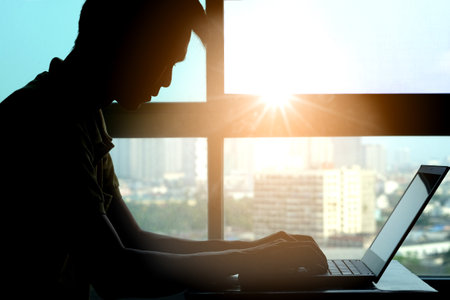 Silhouette of man work computer at desk in office. Health conceptの写真素材