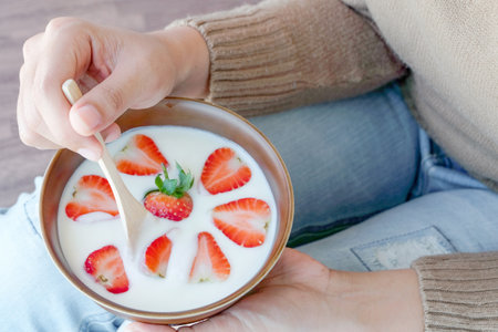 Hand of woman holding bowl of fresh strawberry and yogurt .Concept of healthy diet and weight controlの写真素材