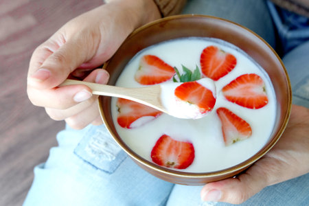 Hand of woman holding bowl of fresh strawberry and yogurt .Concept of healthy diet and weight controlの写真素材