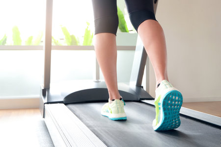 leg of woman running on treadmill in the gym which runner athletic by running shoes. Health and...