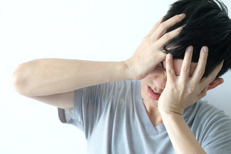 young men have an angry headache as two emotions. White background, health concept.の写真素材