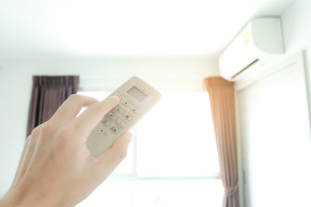 Man's hand using remote control open The air conditioner is cooled to 25 degrees Celsius in his bedroom. Health concepts and energy savingsの写真素材