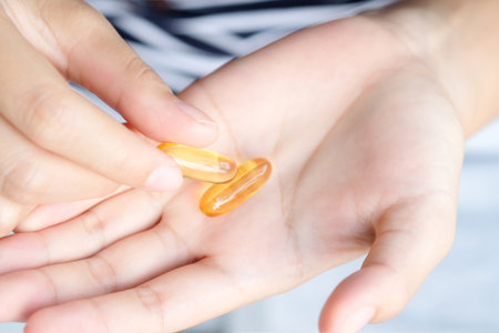 Beautiful woman's hand She is taking vitamin E and fish oil in her hands.の写真素材