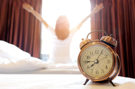 Morning of a new day, alarm clock wake up man sitting in the room. A man stretch the muscles at window. Health and care conceptsの写真素材