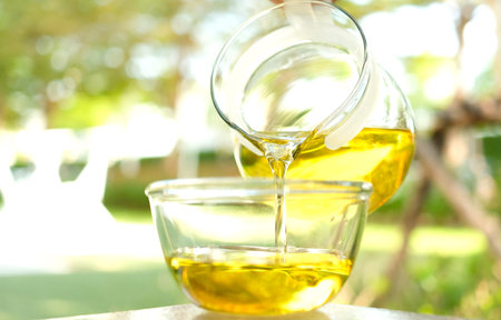 Pouring olive oil in the a glass bowl at stone kitchen and inside green garden view. Prepare for cooking concept. Healthcare and Beauty Concept.の写真素材