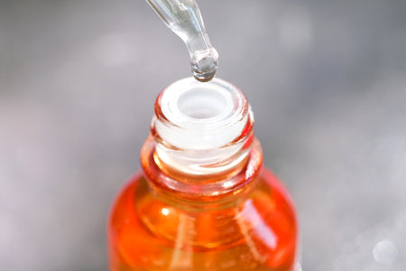 Dropping serum collagen moisturizer of face into clear yellow bottle soft light background. Protector skin Treatment facial essence oil, Vitamin C. Beauty and spa Conceptの写真素材