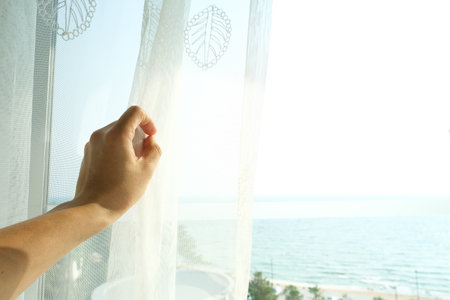 The woman woke up early. She stood at the window in her bedroom and she lifted up both arms to refresh. In the morningの写真素材