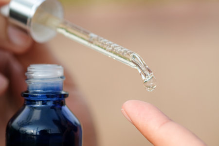 hands of a beautiful woman Dropping serum collagen moisturizer of face into clear gold bottle soft light background. Protector skin Treatment facial essence oil, Vitamin C. Beauty and spa Conceptの写真素材
