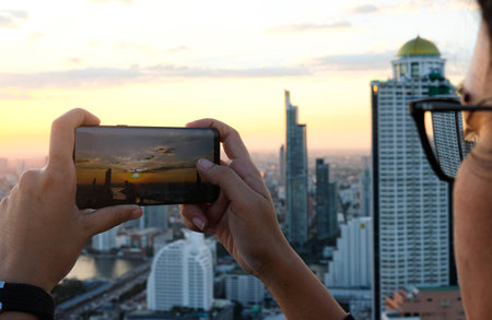 Young people take pictures of the buildings in the city. Sunrise time He uses a high-angle recording photo phone.Travel concepts and technologyの写真素材