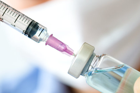 doctor's hand holds a syringe and a blue vaccine bottle at the hospital. Health and medical concepts.の写真素材