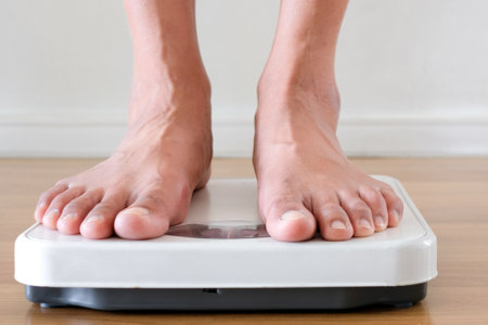 Legs of women standing on scales weight background fitness room. Concept of healthy lifestyle and...