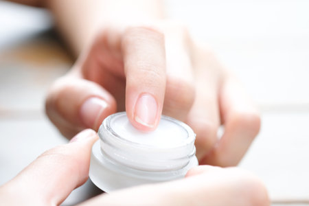Hand of woman holding moisturizer cream and serum. She applying a facial cream , essential , oil , lotion and body cream for skin care, close up view and blur background. Beauty and Healthy Concept.の写真素材