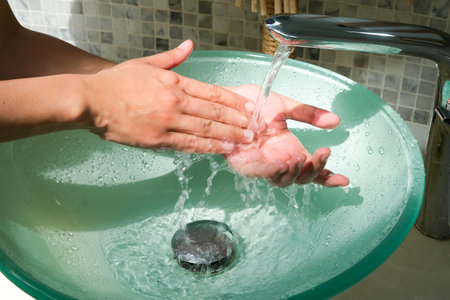 Hands of woman wash their hands in a sink with foam to wash the skin and water flows through the hands. Concept of health, cleaning and preventing germs and coronavirus from contacting handsの写真素材