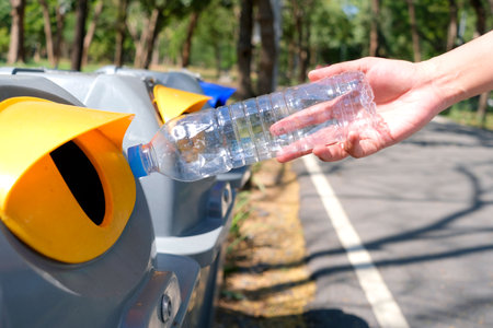 Please dispose of plastic bottle into the tank. A man throw rubbish in the trash can by separate...