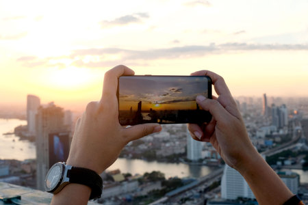 Young people take pictures of the buildings in the city. Sunrise time He uses a high-angle recording photo phone.Travel concepts and technologyの写真素材