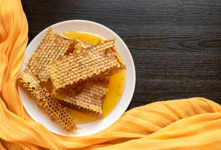 Honeycombs in white plate on the wooden table. Natural organic bee product. Healthy lifestyle. Copy space for your text. Close-up photo.の写真素材