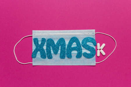 Medical protective mask on pink background. Inscription Xmas. Christmas and New Year card, banner,...