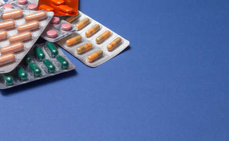 Different medicines: tablets, pills in blister pack, medications drugs on blue background. Close-up photo, copy space. High quality photoの写真素材