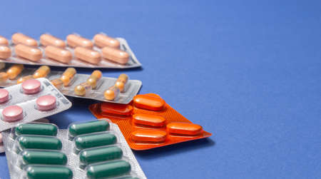 Different medicines: tablets, pills in blister pack, medications drugs on blue background. Close-up...