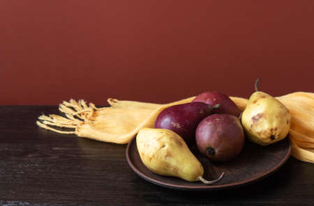 Ripe organic red and yellow pears in a clay bowl on a dark wooden background. Fresh pear closeup. Background with yellow and red pears. High quality photoの写真素材