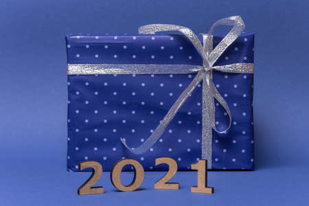 Box with gift in wrapped in blue paper with polka dots with silver bow on blue background....