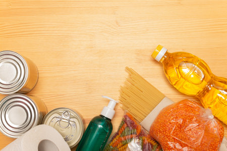 Food delivery service. Buy products online during quarantine. Healthy food and antiseptic on wooden background. Sunflower oil, tomatos, pasta, bread, lentils, caned food, toilet paper, sanitizer.の写真素材