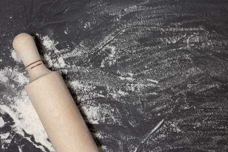 Rolling pin and white flour on black stone table. Banner for web with free space for your text....