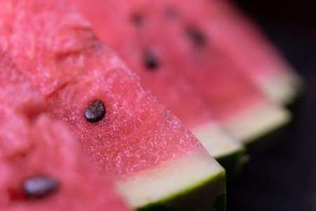 Pieces of refreshing watermelon on a dark wood background. Close-up photo. Fruit texture. Selective focus. High quality photoの写真素材
