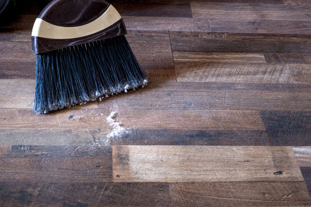 Close-up of a broom sweeping dust and dirt on a wooden floorの写真素材