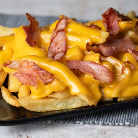 French fries with bacon and cheese on a wooden background. Selective focus.の写真素材