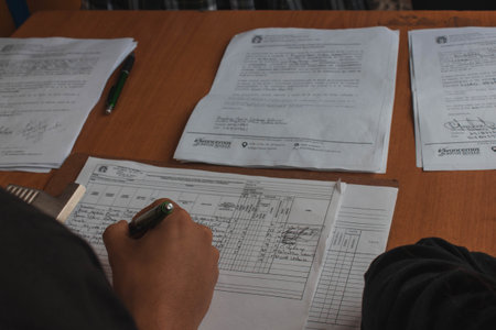 Closeup of a man writing notes on a desk at home.の写真素材