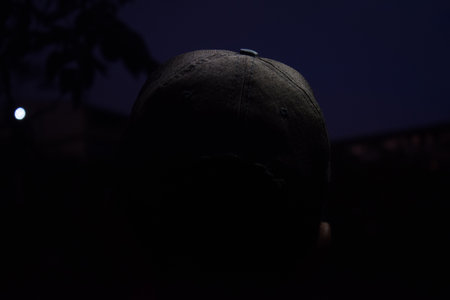 Silhouette of a man wearing a baseball cap in the darkの写真素材