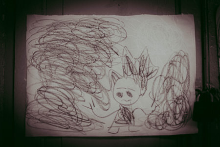 Child drawing on a white sheet of paper on a wooden background.の写真素材