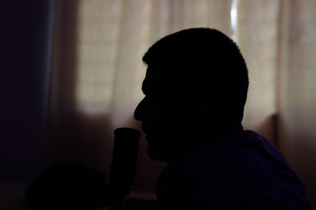 Silhouette of a man singing into a microphone at home.の写真素材