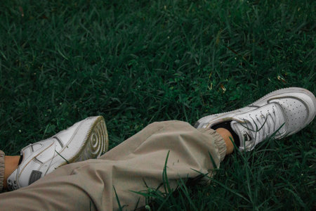Legs of man in sneakers lying on the grass in the parkの写真素材
