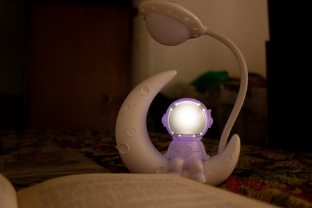 A lamp with a candle and a book on the table in the darkの写真素材