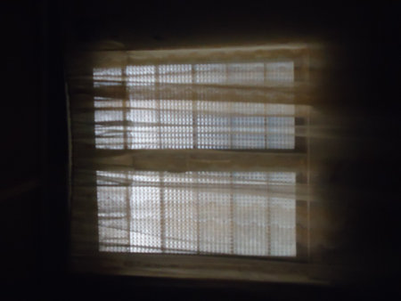 silhouette of a window with blinds in a dark roomの写真素材