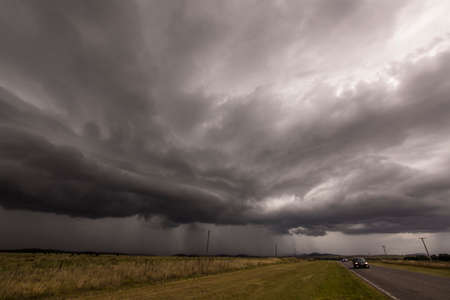 Heavy Rain and a dark sky over the road in a rural area near Sierra de la Ventana, one of the few...