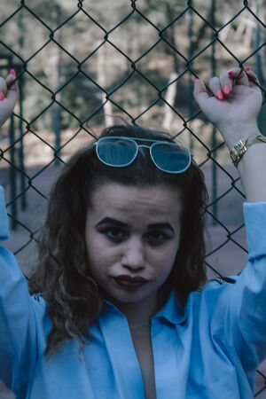Portrait woman with curly hair on a metal rack. Thick lips painted with glasses.の写真素材