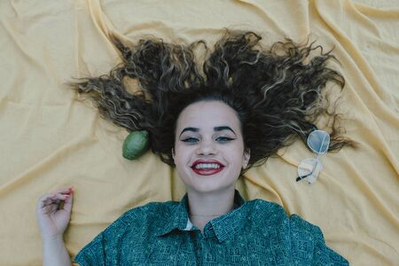 Vertical side profile top above high angle photo beautiful she her lady lying down show perfect shiny ideal hair above head slim skinny wearing formal wear yellow cloth background backgroundの写真素材