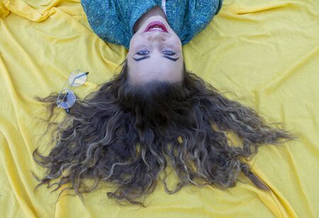 Vertical side profile top above high angle photo beautiful she her lady lying down show perfect shiny ideal hair above head slim skinny wearing formal wear yellow cloth backgroundの写真素材