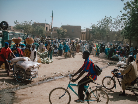 Timbuktu, Mali, Africa - February 3, 2008: Boy crossing a bicycle through the city market with a Spanish soccer team shirt.のeditorial素材