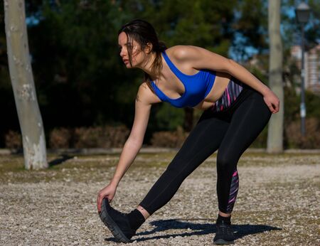 Young latin woman training with leggins and blue top in the park. Healthy life style. Fit woman concept. Woman exercising her body.の写真素材