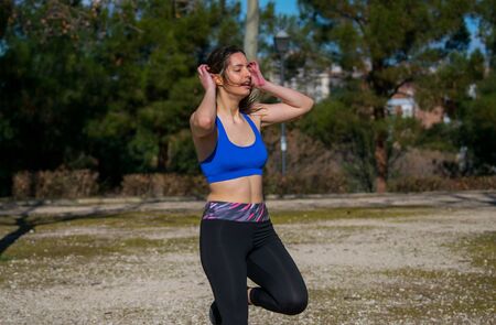 Young latin woman training with leggins and blue top in the park. Healthy life style. Fit woman concept. Woman exercising her body.の写真素材