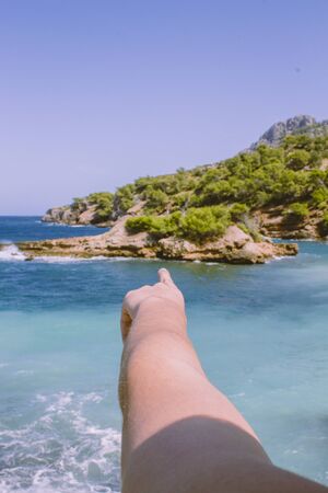 Traveler woman pointing direction on her new adventure to the island. Close-up. Point of view shotの写真素材